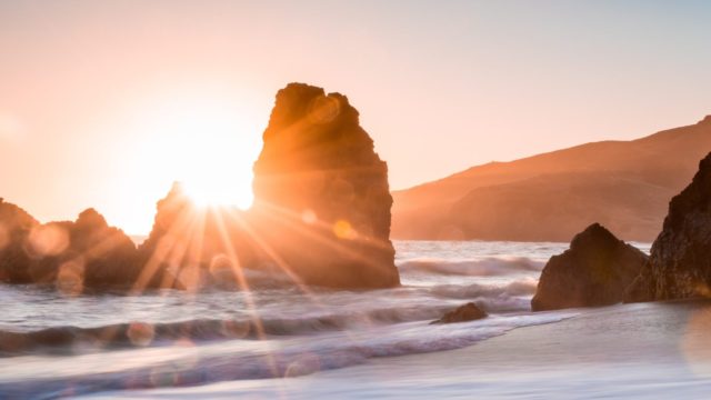 golden hour photography of rock formation on body of water