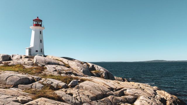 white and red lighthouse on brown rocky shore under blue sky during daytime